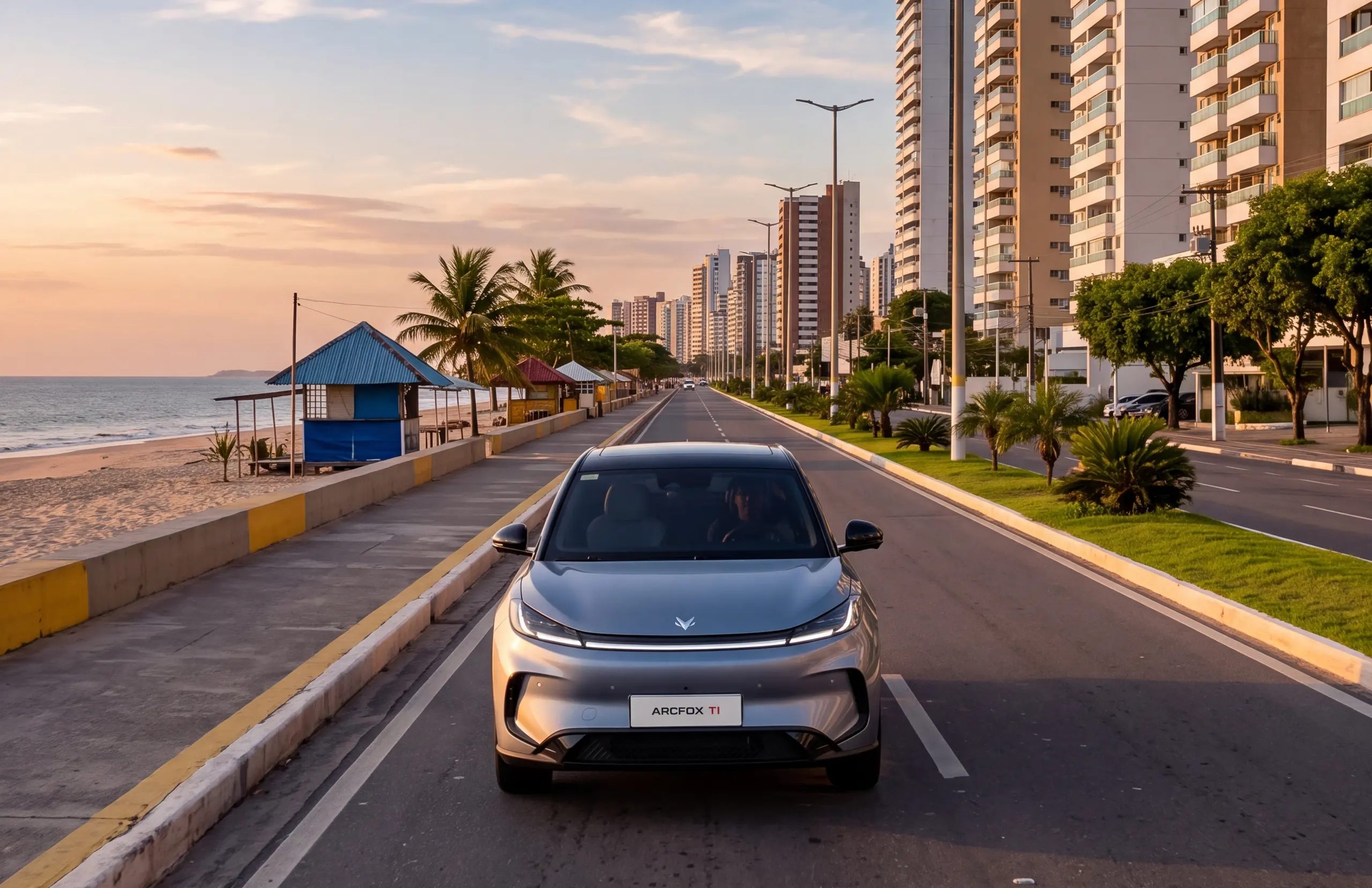 Arcfox T1 na avenida da orla da Ponta d’Areia, em São Luís, ao entardecer, com a praia e os prédios ao lado.